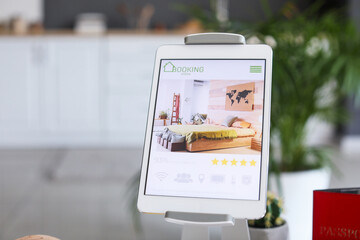 Open page of online booking service on screen of tablet computer at home