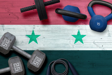 Syria sports club concept. Top view of heavy weight plates with iron bar on national background.