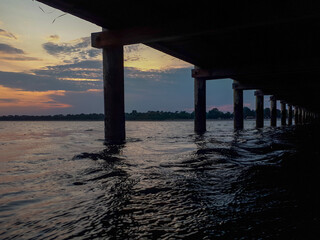 Scenic view of sunset underneath pier in the water in Grado, Italy. Architectural silhouette against evening sky.
