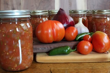 fresh tomatoes and peppers and jars of home canned spicy salsa