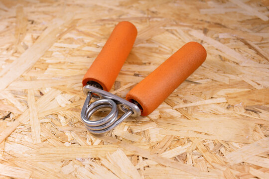 Orange palm trainer espander on wooden surface of pressed sawdust