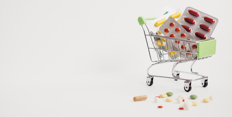 Shopping cart filled with pills. white background. Concept: full set of medicines in the store.
