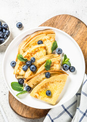 Crepes with blueberries at white table.