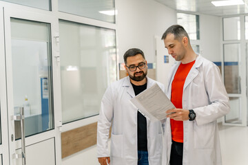 Obraz premium Doctors are discussing medical issues. Standing at hospital with papers in hands.