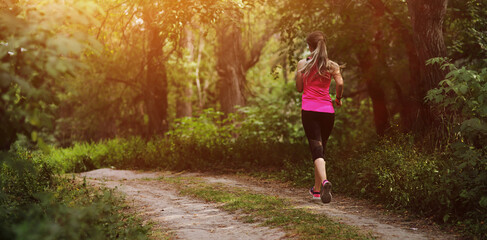 Young fitness woman running in the morning forest trail. Healthy fit living.