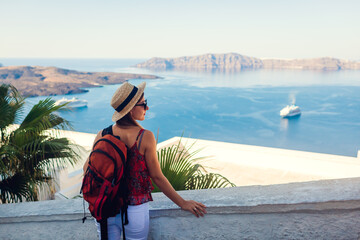 Woman traveler looking at Caldera landscape, Santorini island, Greece. Tourism, traveling, summer...