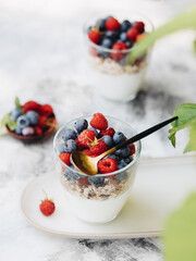 Healthy breakfast. Two glass glasses with yogurt, muesli and fresh berries are on an elongated plate. Nearby are fresh blueberries and raspberries. Summer light breakfast in nature. Healthy diet.