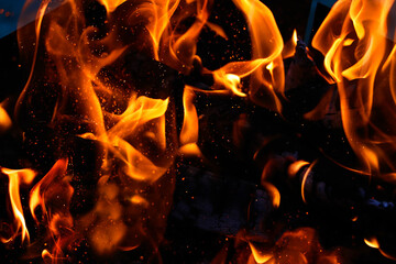 Defocused closeup photography of burning flame with sparkles.Overlay layer.Isolated on black.Burning bonfire. A picnic concept in nature.Selective focus.Blurred background.