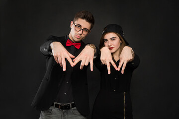 Teenage smiling rap couple in black clothes and a black cap. Isolated over a black background color