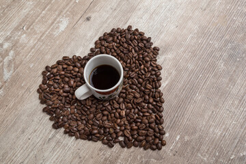 top view of a cup with coffee beans, heart shape on a wood table