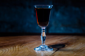 Dark red tincture or liqueur in a glass is on the table in the night bar
