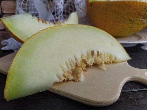 Large pieces of cut melon with seeda on a wooden table