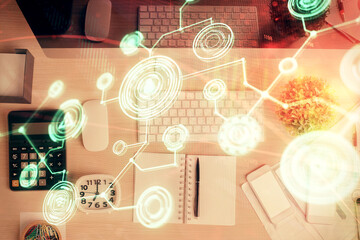Fototapeta premium Social network hologram drawings over computer on the desktop background. Top view. Multi exposure. Concept of people connection.