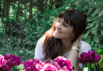 Naklejka premium Beautiful happy girl in the garden on a background of purple large tulips. Smile, sun on hair, profile view, Keukenhof park netherlands