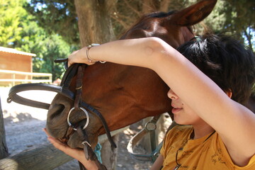 Une jeune femme plaçant le mors à son cheval © raymond