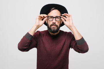  pensive young man in a burgundy sweater in black hat in the studio on a white background