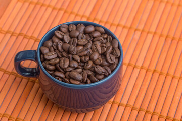 blue mug with coffee beans on an orange texture, studio