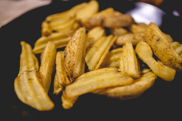 Close up of home made rustic french fries and in a black plate
