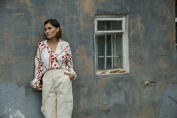 Portrait of a young brunette woman in a white fashion suit with a red print