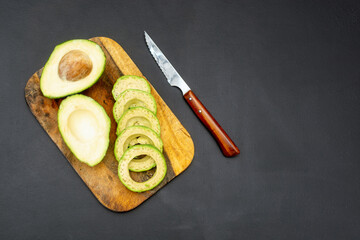 Fresh avocado and a knife with a wooden handle.