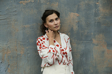 Portrait of a young brunette woman in a white fashion suit with a red print