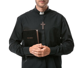 Handsome priest with Bible on white background