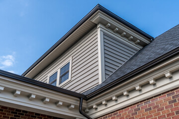 Beige cornice horizontal decorative molding crowning a new brick building with brown metal gutter