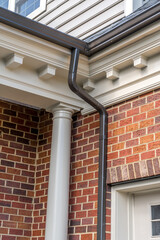 Beige cornice horizontal decorative molding crowning a new brick building with brown metal gutter...
