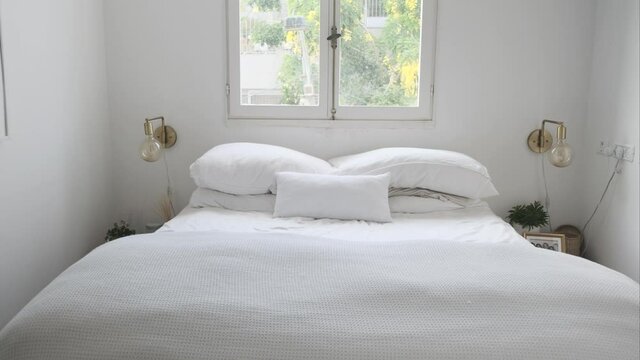 Beautiful white bedroom. An empty bed next to white big window in gorgeous abstract hotel room. relaxing vacation