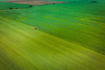 Tractor mowing green field, aerial view
