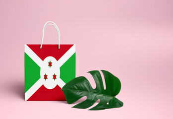 Burundi shopping concept. National cardboard shopping bag with monstera leaf and pink background. Online shopping theme.