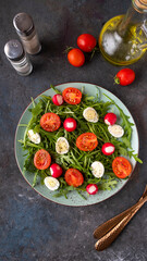 Diet salad with arugula, quaill eqqs and cherry tomatoes. Vegetables salad on a plate. Top view
