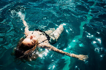 Young hot woman resting alone. Girl swimming in water and enjoying. Rest and relax under the sun outside. Resort spa place and joy because of swimming. Spa procedure.