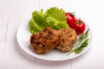 meatballs with vegetables on a white plate on a white wooden background