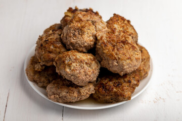 meatballs on a white plate on a white wooden background