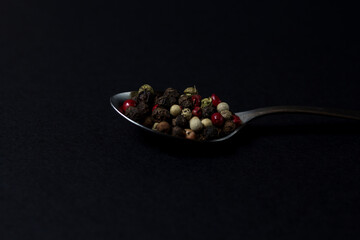 various types of pepper in a spoon on a dark background. hot seasonings for cooking.