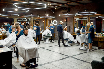 Modern barbershop. Professional barbers serving clients in the modern loft style barber shop....