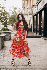 Girl in red dress stands on a street. Soft selective focus