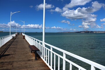 Fototapeta na wymiar wooden pier with white railing, blue sea and blue sky