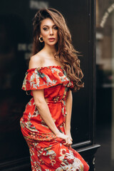 Girl in red dress stands on a street. Soft selective focus