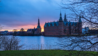 Frederiksborg castle on the sunset, with lake and tree in the foreground, Hillerod, Denmark