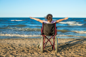 Caucasian little girl on the wheelchair on summer by the sea.Disabled teenager in a wheelchair on...