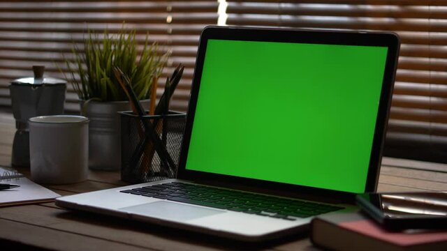 4K dolly shot. A laptop computer with a key green screen set on work office table.