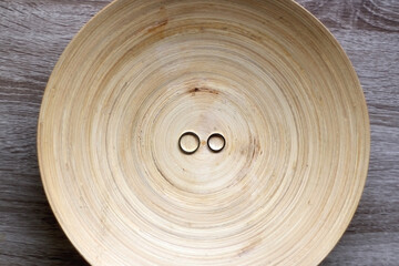 Fototapeta na wymiar Gold wedding rings on rustic wooden plate. Top view.