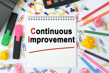 On the table is a calculator, diary, markers, pencils and a notebook with the inscription - Continuous Improvement