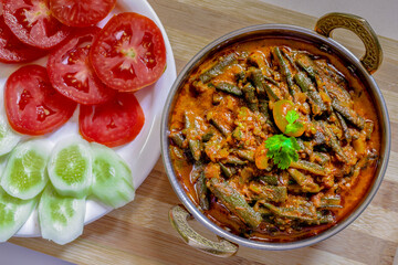 Indian food. Okra, bhindi, ladyfinger cooked with red gravy. Red gravy based Indian sabzi served with cucumber and tomato salad.