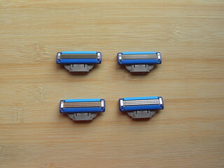 4 blue color shaving razor blade cartridges kept on wooden table