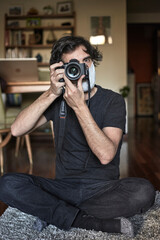 Photographer with face mask taking a photo inside his house.