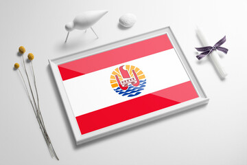 French Polynesia flag in wooden frame on table. White natural soft concept, national celebration theme.