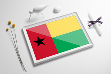 Guinea flag in wooden frame on table. White natural soft concept, national celebration theme.